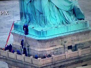 A tüntető egy ideig a Szabadság-szobor jobb lába alatt húzta meg magát. (Képernyőfotó, CNN)